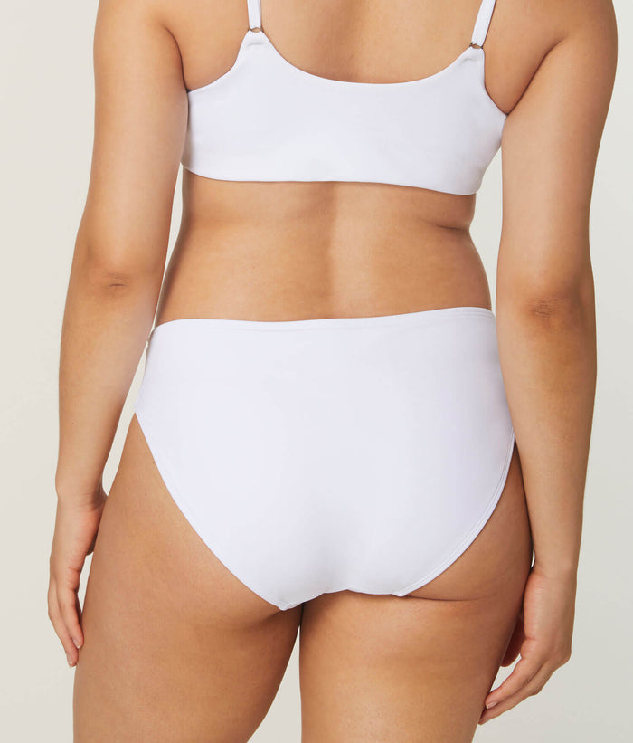 Model wearing Andie Swim white eco-nylon bikini bottom, low rise, medium seat coverage, flattering back view.