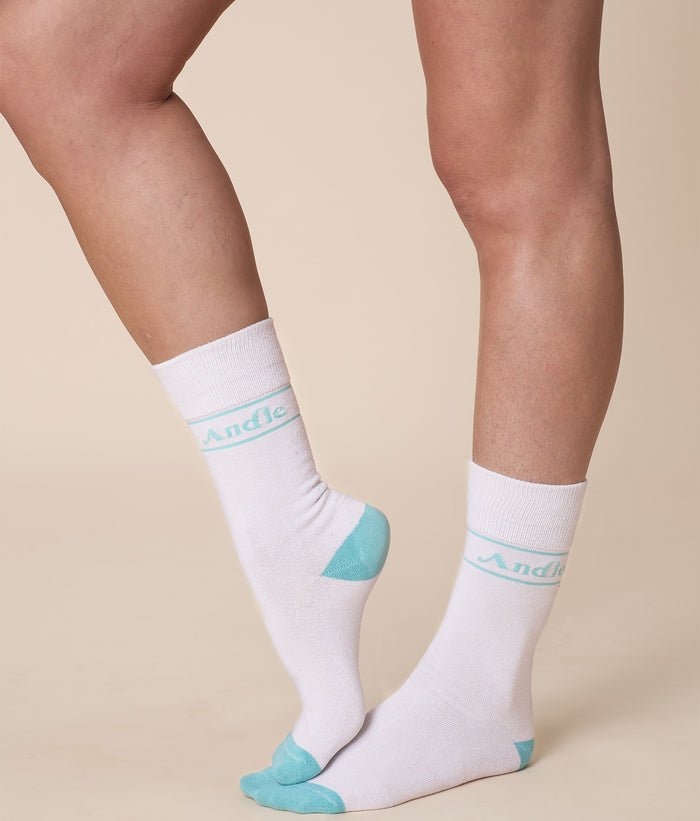 White cotton Andie socks with teal accents and 'Andie' logo along the side. Comfortable and stylish, perfect for casual wear.