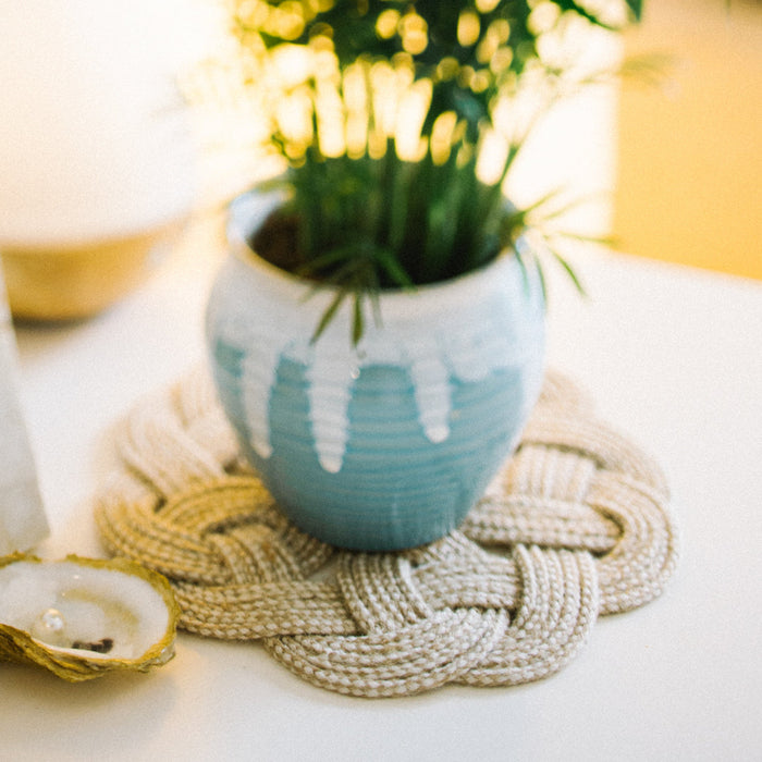 Handmade cotton trivet in a natural color styled under a vase | Home Decor Gifts that Give Back