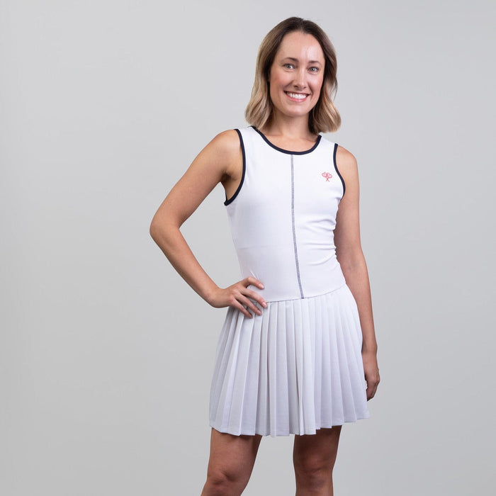 Woman wearing a white dress with navy trim on a gray background