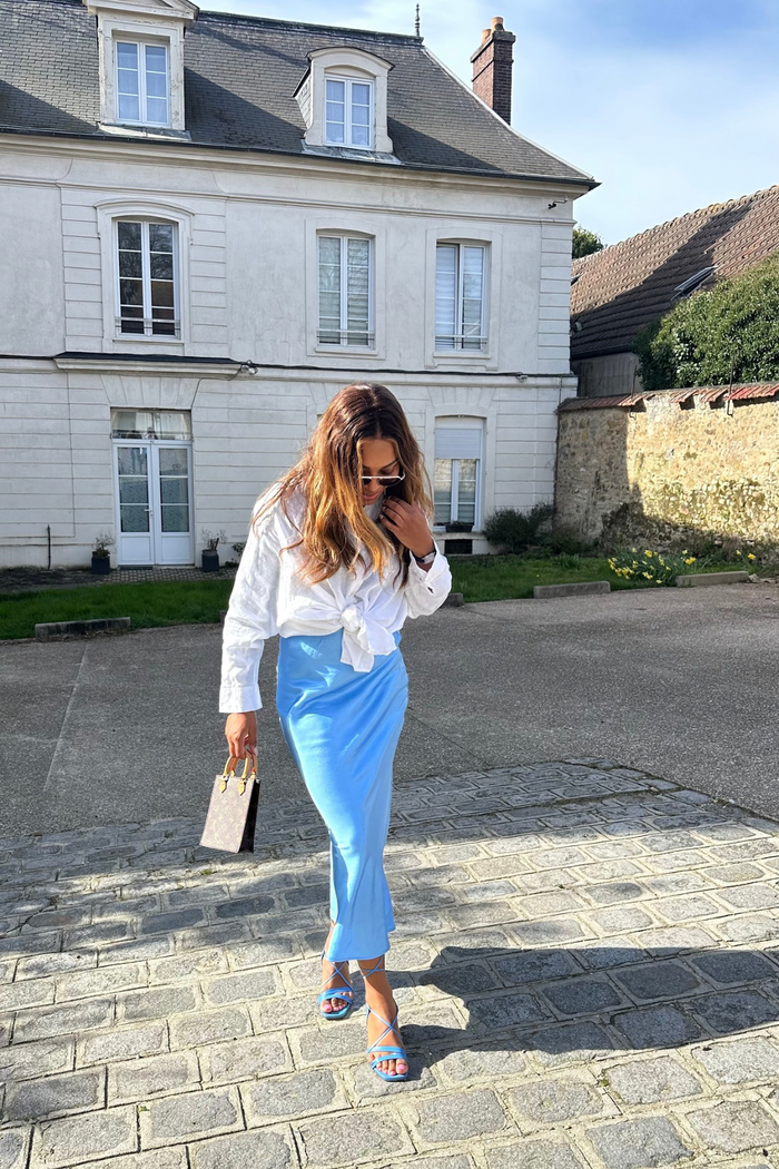 Lifestyle shot with the modest satin flared skirt in light blue paired with open heeled sandals for a fresh modest cut look