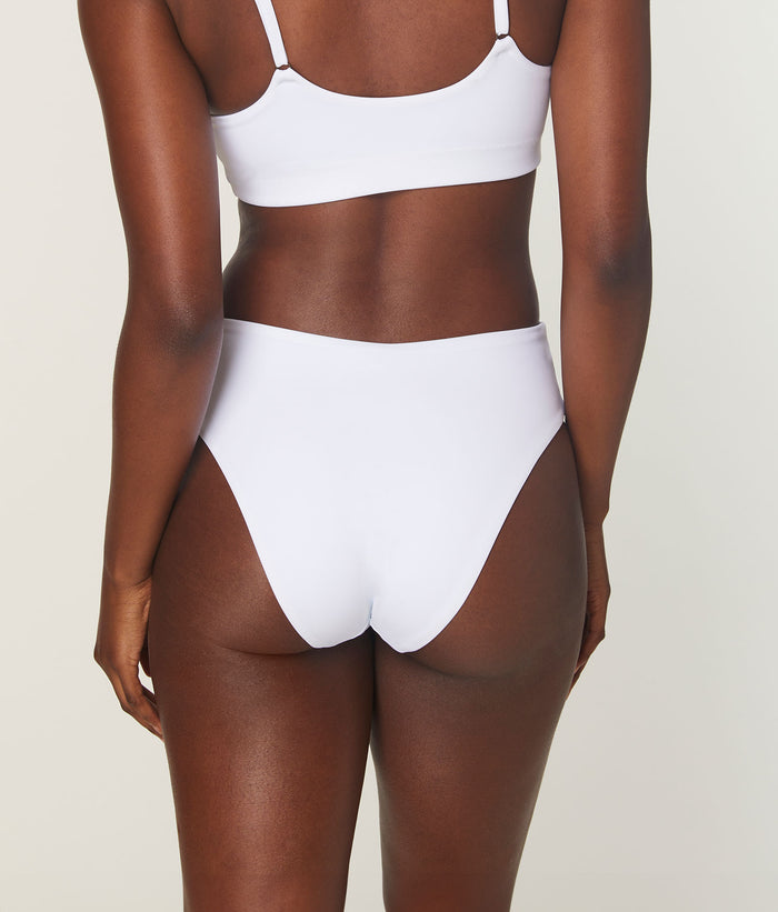 Back view of model in white 90s high-waist bikini bottom by Andie Swim, highlighting cheeky seat coverage and compressive fabric.