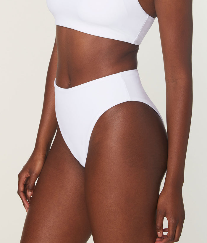 Side profile of model in white Andie Swim 90s-inspired high-waist bikini bottom, showcasing the sculpting fabric and cheeky fit.