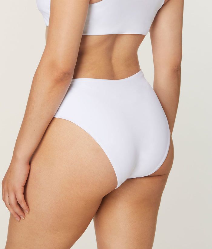 Side view of model wearing Andie Swim white 90s high-waist bikini bottom with high-rise fit and cheeky seat coverage.