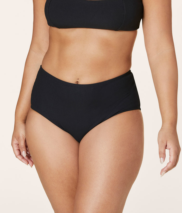 Model wearing Andie Swim eco ribbed black high waisted bottom, showcasing sculpting fit, full seat coverage, and flattering high-rise cut.