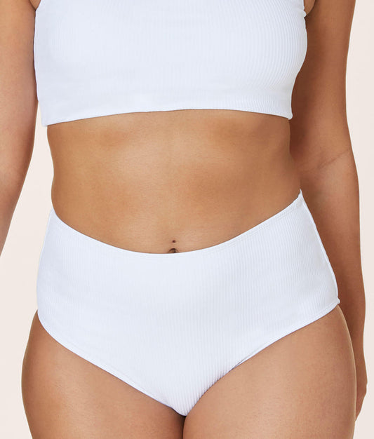 Andie Swim high-waisted ribbed white bikini bottom with low leg cut and full coverage, modeled from the front. Compressive, sculpting fit just below the belly button