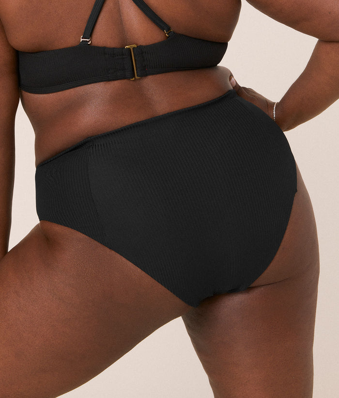 Andie Swim high-waisted cheeky black bikini bottom with full back view, highlighting the cheeky cut and ribbed fabric. Very high rise for a flattering fit