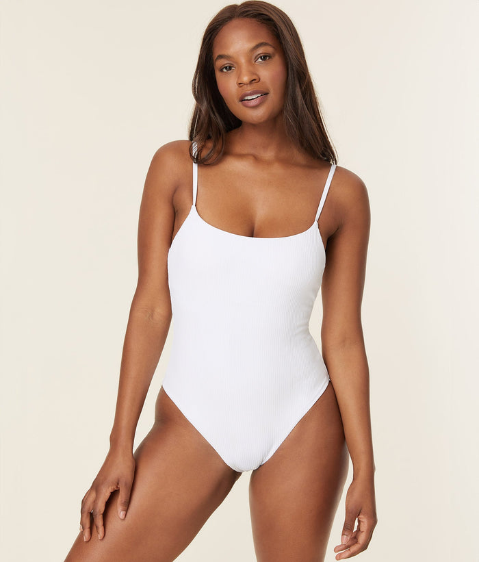 Front view of a woman wearing the Jetties one-piece in eco ribbed white fabric, highlighting the scoop neckline and compressive fit.