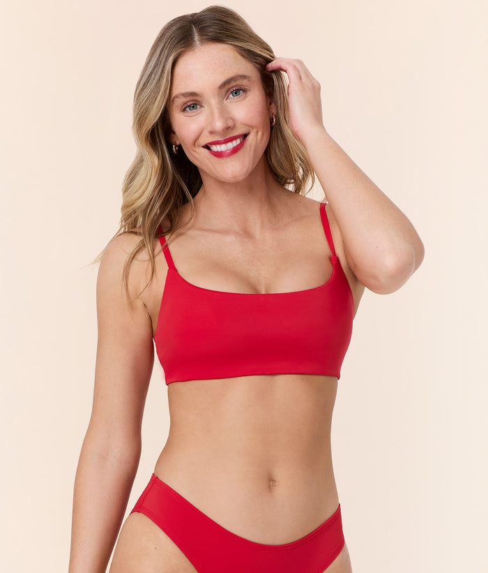 Model smiling in Andie Swim's Maui Bikini Top in Cherry Red, back view showing adjustable straps and a secure fit.
