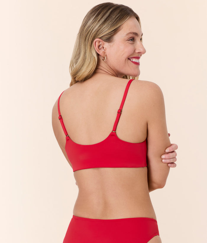 Model smiling in Andie Swim's Maui Bikini Top in Cherry Red, back view showing adjustable straps and a secure fit.